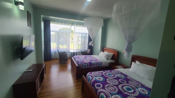 A hotel room with two beds, a TV, a small table, and a chair.