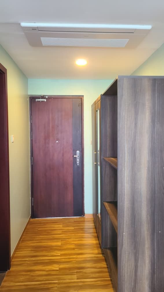 Un pasillo con piso de madera, una puerta cerrada y una estantería empotrada.