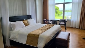 Habitación de hotel con una cama grande, una mesita y vistas al exterior.