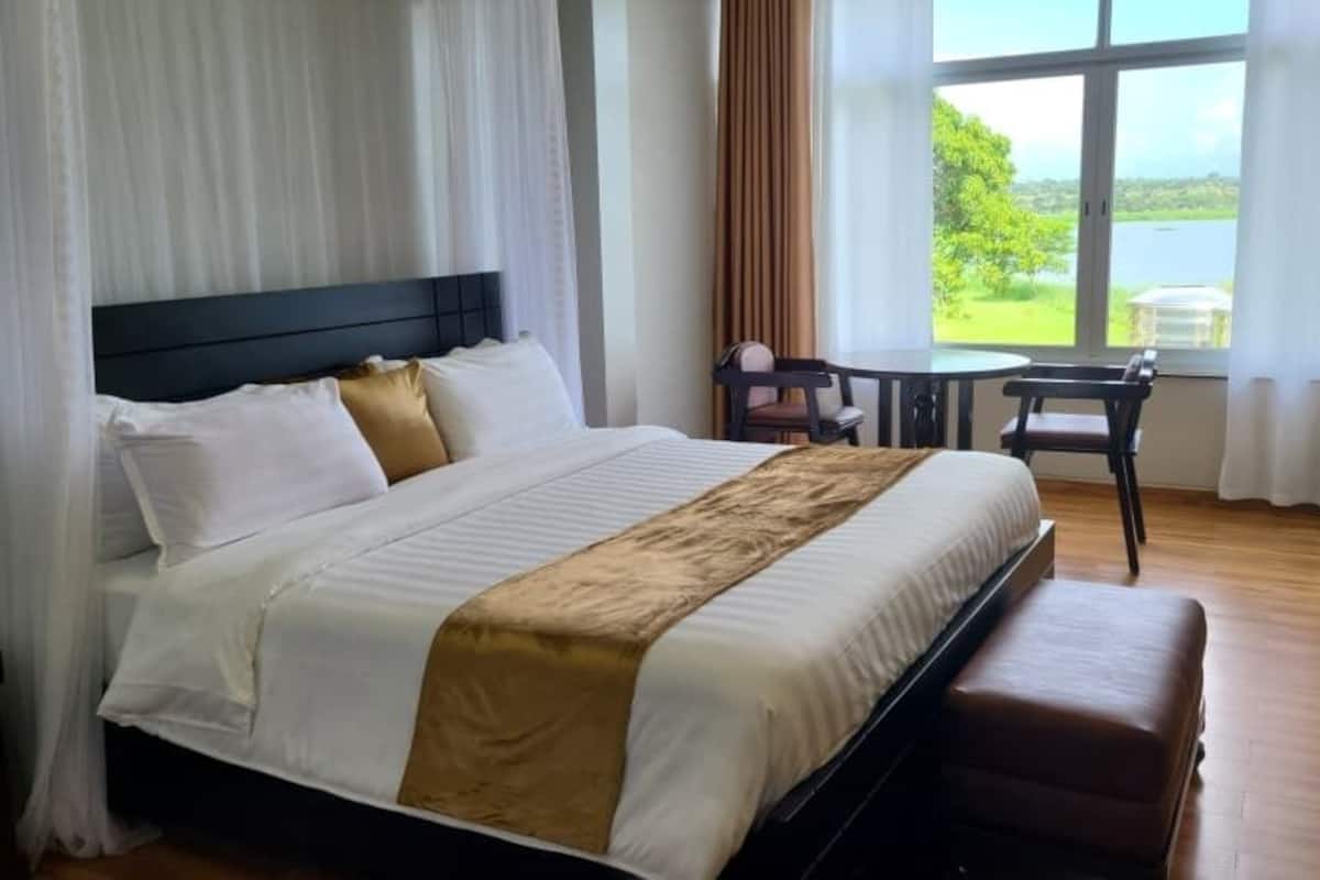Ein Hotelzimmer mit einem großen Bett, einem kleinen Tisch und Blick ins Freie.