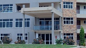 Un edificio de varios pisos con techo plano, ventanas amplias y un balcón en el segundo nivel.