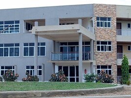 Un edificio de varios pisos con techo plano, ventanas amplias y un balcón en el segundo nivel.