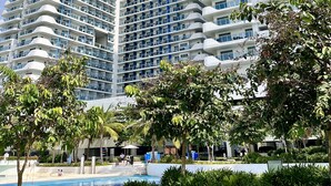 A modern high-rise building with multiple balconies and a swimming pool area in the foreground. - Luxury Penthouse in CBD w/ Wave Pool, 7ft Billiards & Wide Balcony for Getaways (San Fernando)