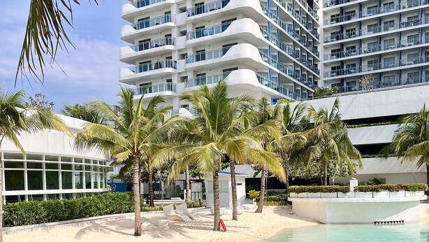 A modern hotel with a pool, palm trees, and a sandy beach area. - Luxury Penthouse in CBD w/ Wave Pool, 7ft Billiards & Wide Balcony for Getaways (San Fernando)