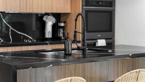 Eine Küche mit schwarzer Arbeitsplatte, einem modernen Wasserhahn und Holzschränken.