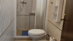 Une petite salle de bain avec des toilettes, une douche et un lavabo.