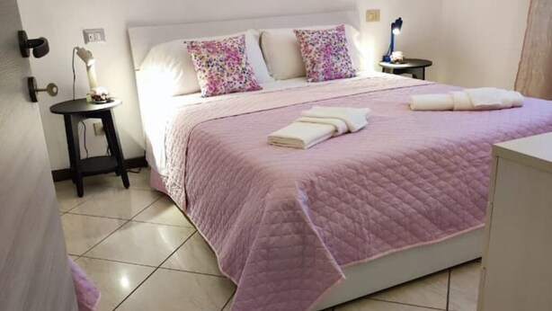 Une chambre à coucher avec un lit, une table de chevet, une lampe et un luminaire fixé au mur.