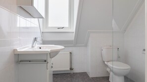 Een moderne badkamer met een witte wastafel, toilet en een raam voor natuurlijk licht.