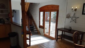 A wooden staircase leading to a glass door, a wooden table with a chair, and a star-shaped wall decoration. - Comfortable gite in the beautiful Brittany countryside (Bignan)