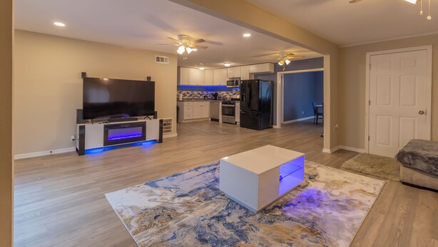 Una sala de estar moderna con un televisor de pantalla plana, una mesa de centro blanca y una alfombra estampada.