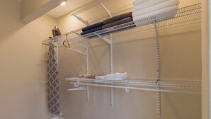 Un lavadero con estanterías metálicas, una cortina estampada y suelo de baldosas.