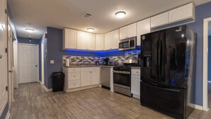 Una cocina moderna con armarios blancos, electrodomésticos de acero inoxidable y un refrigerador negro.