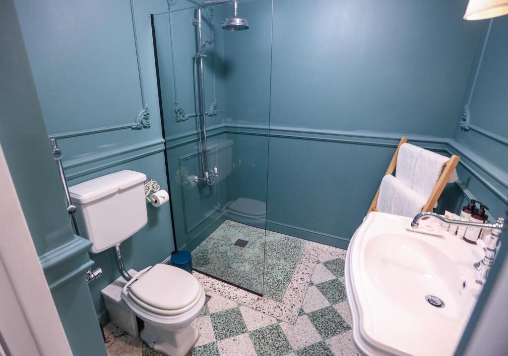 A bathroom with a glass-enclosed shower, a toilet, and a sink.