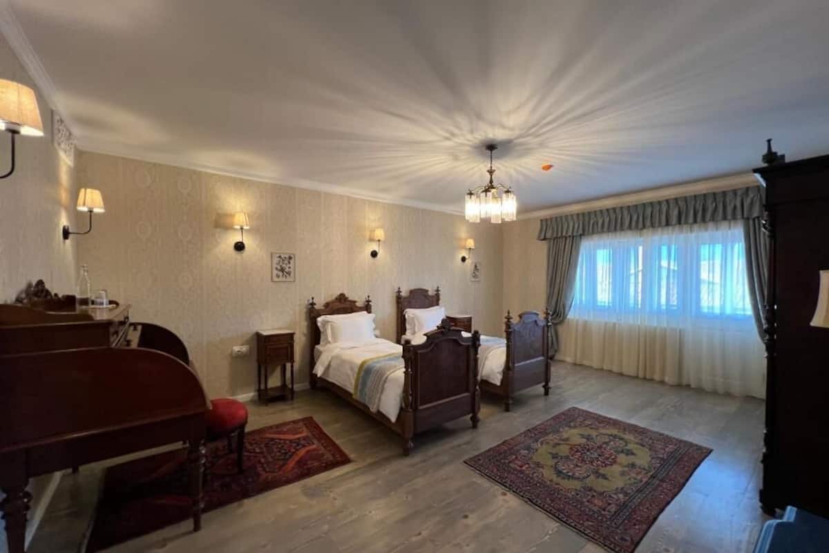 Un dormitorio tradicional con dos camas de madera, un escritorio y un piano.