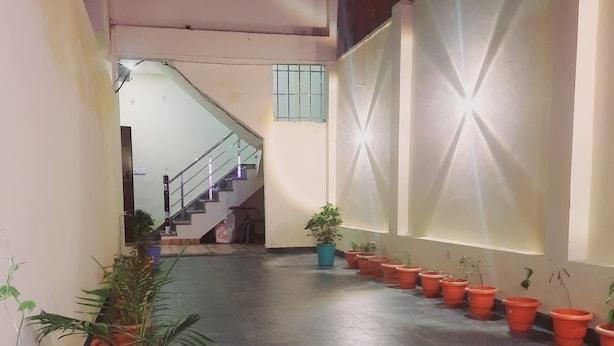 Un pasillo con escaleras, plantas en macetas y suelo de baldosas.
