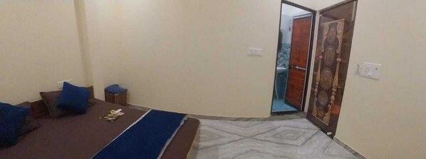 Una habitación con una cama, una mesita y una puerta que da a otra estancia.