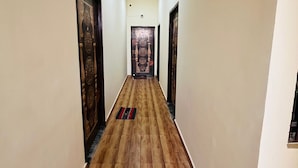 Un pasillo con suelo de madera, paredes color crema y puertas de madera oscura con diseños elaborados.