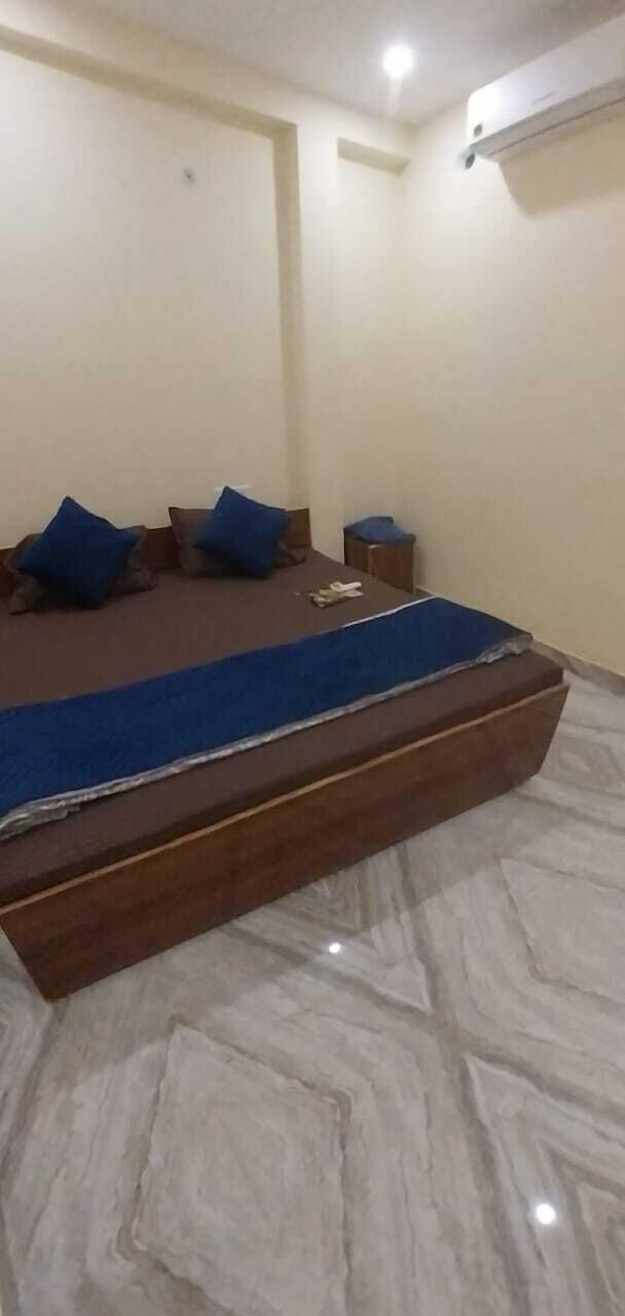 A bedroom with a bed, pillows, a nightstand, and an air conditioning unit.