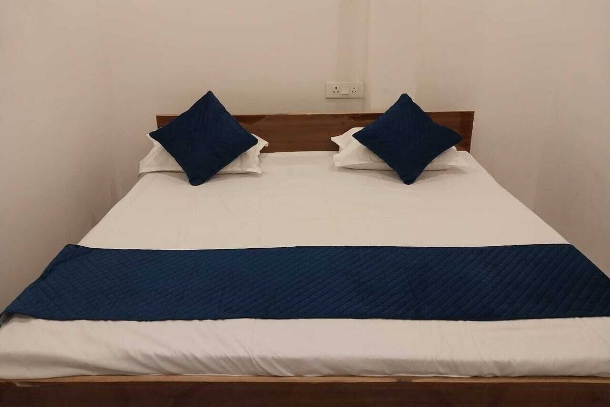 Una cama con una colcha blanca y azul, dos almohadas azules y una manta azul oscuro.