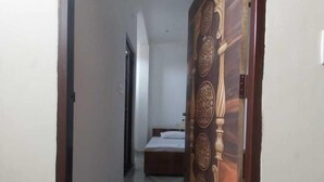 Un pasillo que conduce a un dormitorio con cama y una puerta decorativa.