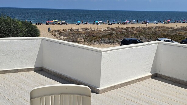 A beach view from a covered deck with a white chair. - Casa Playa Direct (Dénia)