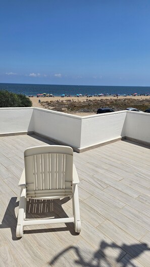 Une vue sur la plage depuis une terrasse couverte avec une chaise blanche.
