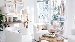 Una sala de estar moderna con mobiliario blanco, un ventanal con vistas y decoración en la pared.