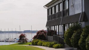 A waterfront building with a balcony, a lawn, and a view of boats. - Clemson|SUPs|ParkPass|PizzaOven|PortmanMarina|EV (Anderson)