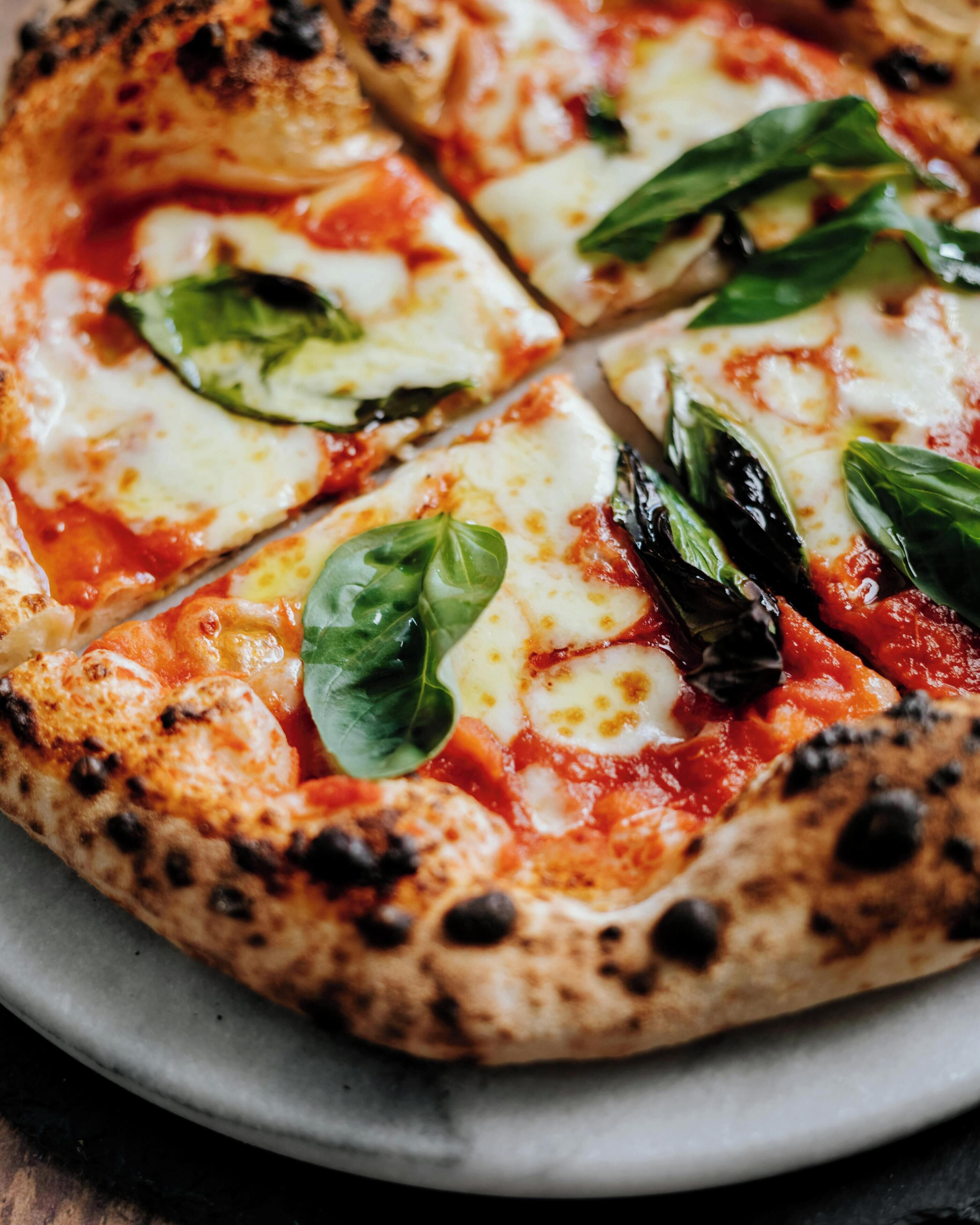 Une pizza garnie de fromage, de sauce tomate et de feuilles de basilic, servie sur une assiette ronde.