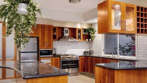 Een moderne keuken met houten kastjes, een roestvrijstalen koelkast, een magnetron, een oven en een spoelbak.