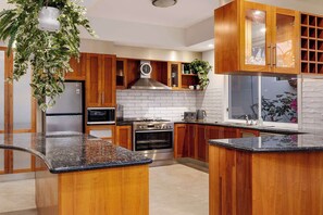 A modern kitchen with wooden cabinets, a stainless steel refrigerator, a microwave, an oven, and a sink. - The Nepean | 100m to Beach, Pool & Fire Pit (McCrae)