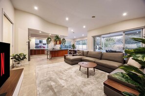 A spacious living area with a large sofa, a coffee table, and a kitchen in the background. - The Nepean | 100m to Beach, Pool & Fire Pit (McCrae)
