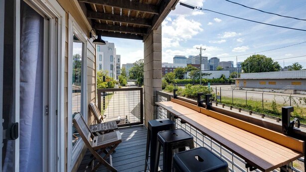 A balcony with a wooden deck, a table, and two bar stools. - Glam Suite w/ Swings | Bach Pad | Pool | Downtown (Nashville)
