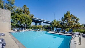 A swimming pool with lounge chairs and a view of a bridge. - Glam Suite w/ Swings | Bach Pad | Pool | Downtown (Nashville)