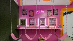 A room with a pink wall, a neon sign, and a mirror above a vanity table. - Glam Suite w/ Swings | Bach Pad | Pool | Downtown (Nashville)