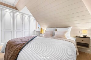 Relax in this serene bedroom with a large bed, nightstand, and window offering a view of the outside.