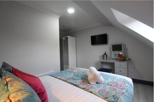 Une chambre comprenant un lit, un bureau, un téléviseur à écran plat et un espace douche.