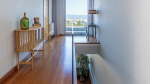 Ein modernes Interieur mit Holzboden, einem Konsolentisch mit Dekoration, einer Lampe und Blick ins Freie durch eine Glastür.