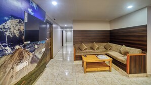 Un vestíbulo moderno con un mural grande en la pared, un sofá modular, una mesa de centro de madera y un televisor.