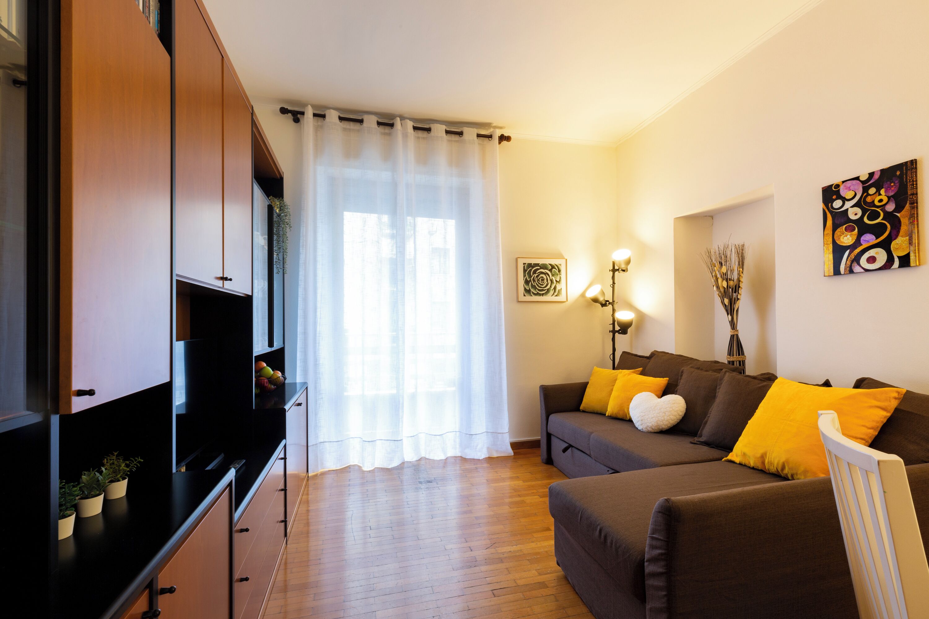 A modern living room with a sofa, a flat-screen TV, and a dining area with a table and chairs.