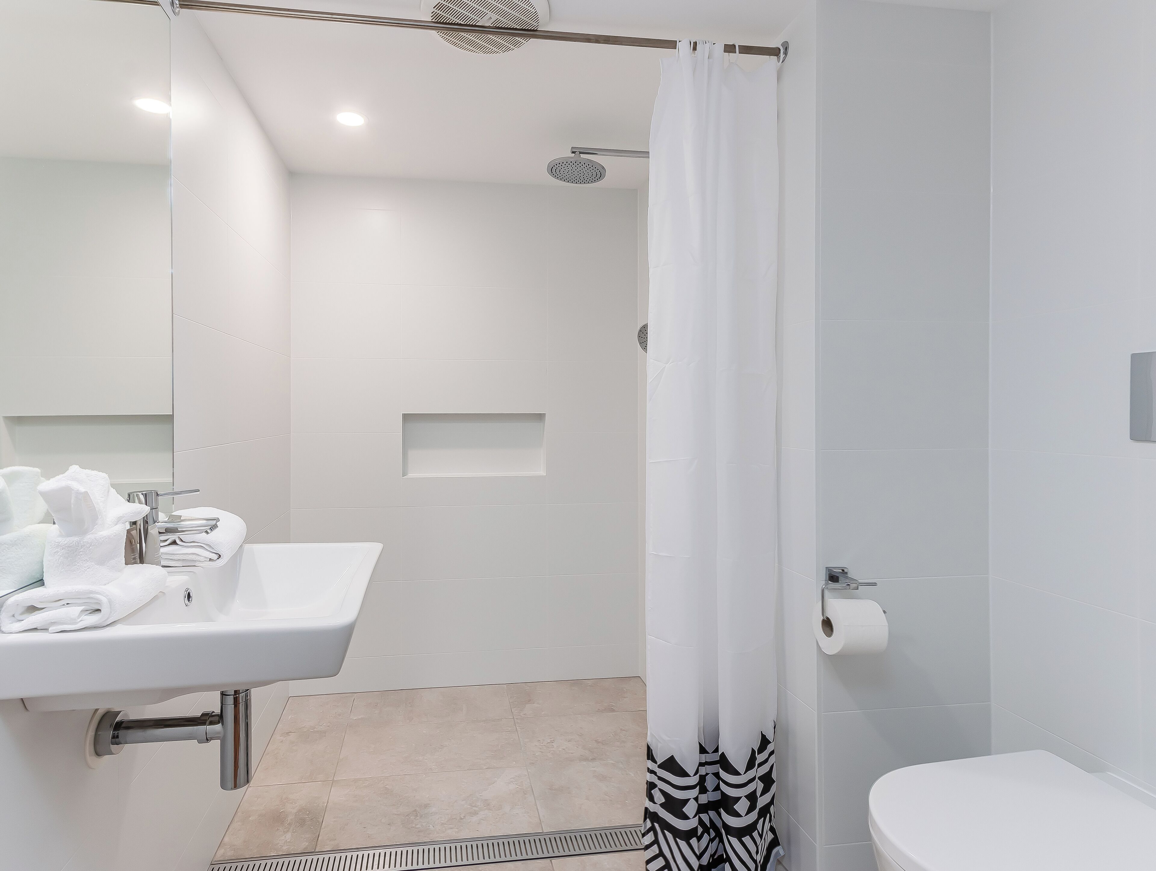 A modern bathroom with a shower, toilet, and sink.