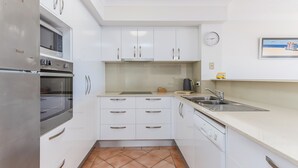 A compact kitchen with white cabinets, a built-in oven, a microwave, and a sink.
