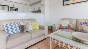 A living room with a beige sofa, a small table, and a colorful striped tablecloth.