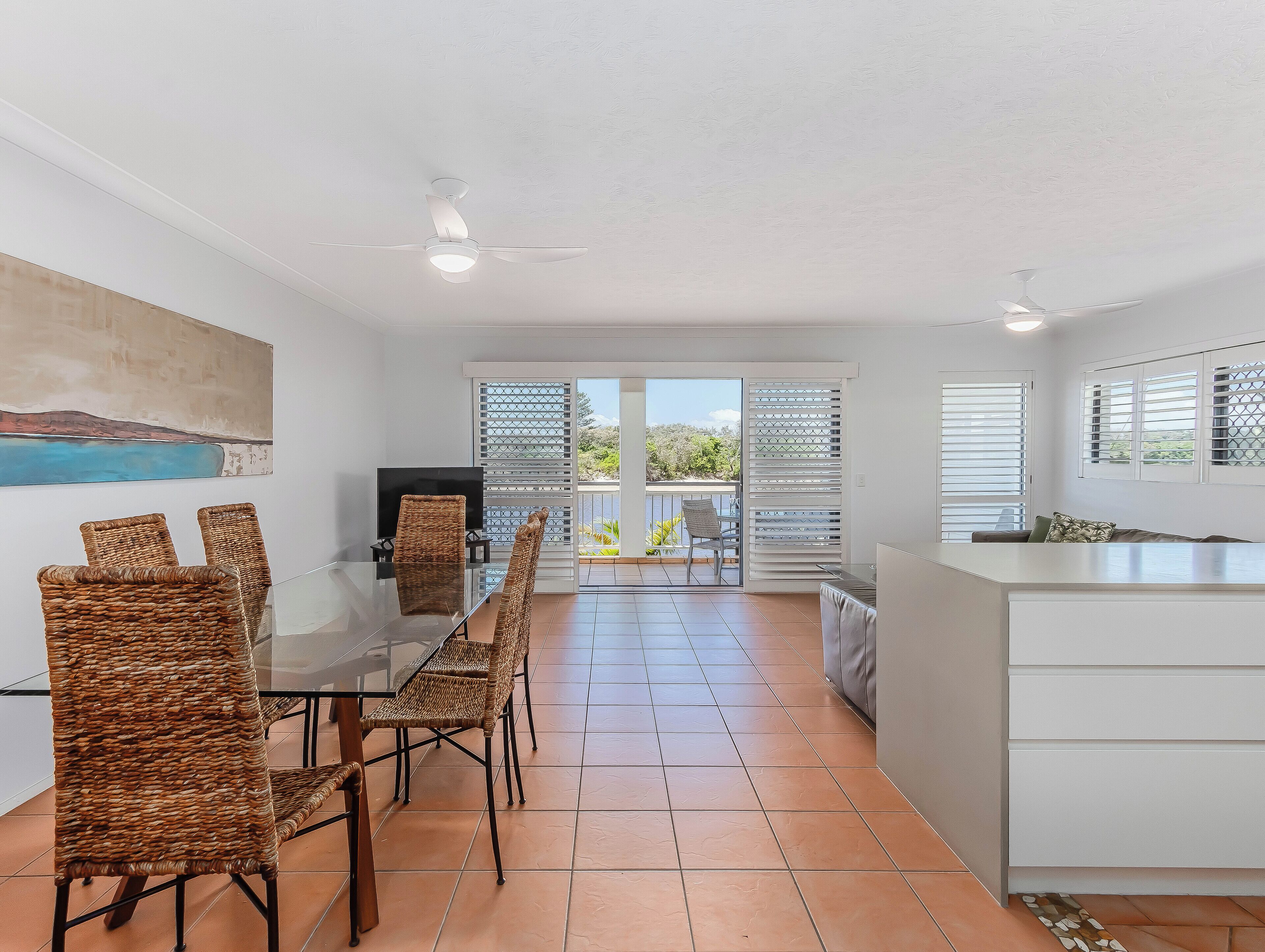 A modern kitchen with a dining area, a ceiling fan, and a view to the outside.