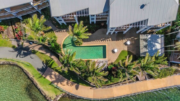 Vista aérea de un resort con piscina, mobiliario exterior y un jardín ajardinado.