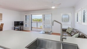 Una cocina moderna con un lavamanos integrado, un ventilador de techo y vistas a un balcón con mobiliario exterior.