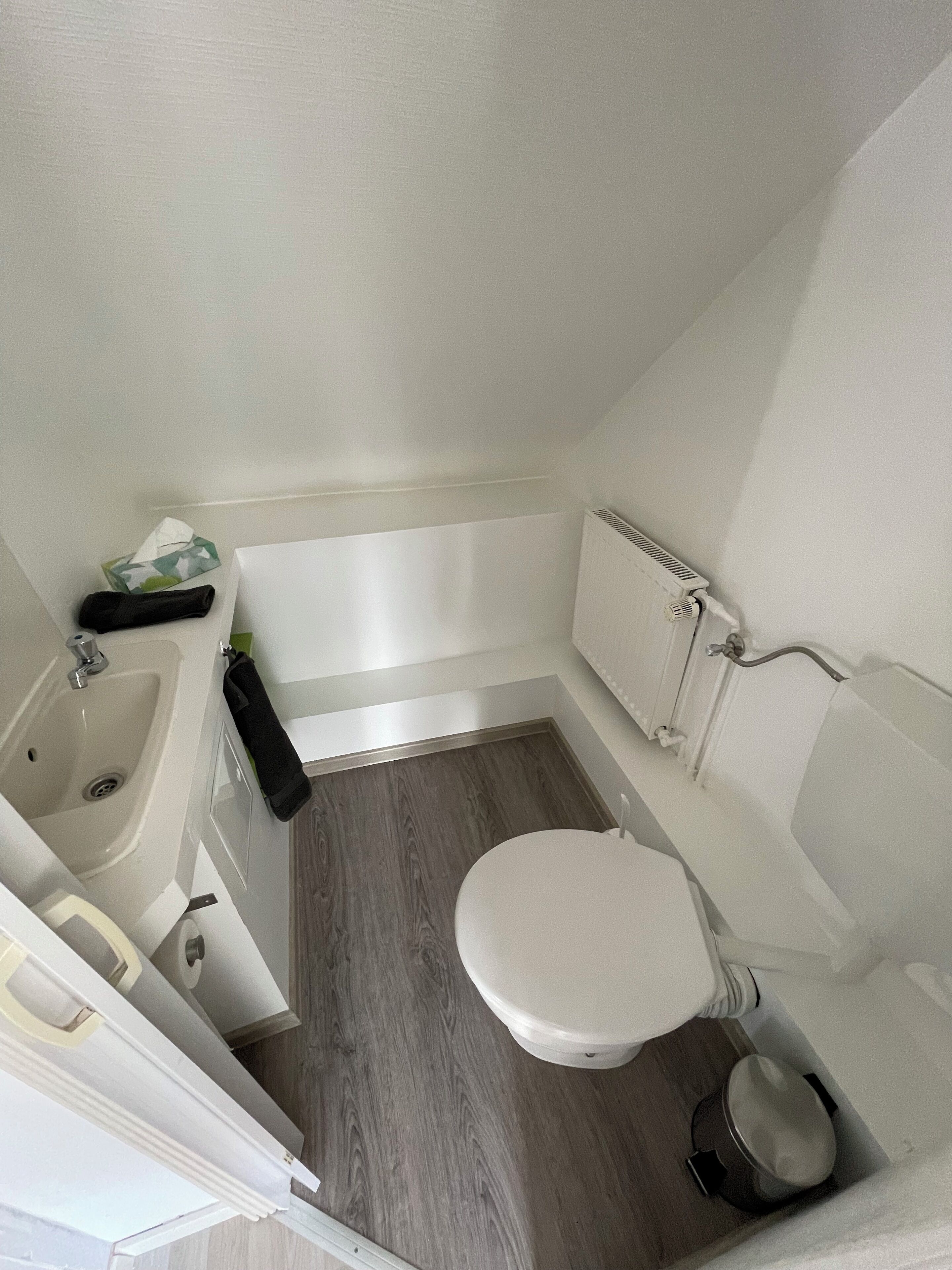 A small, modern bathroom with a white sink, toilet, and bathtub.