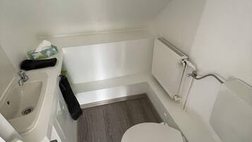 A small, modern bathroom with a white sink, toilet, and bathtub.
