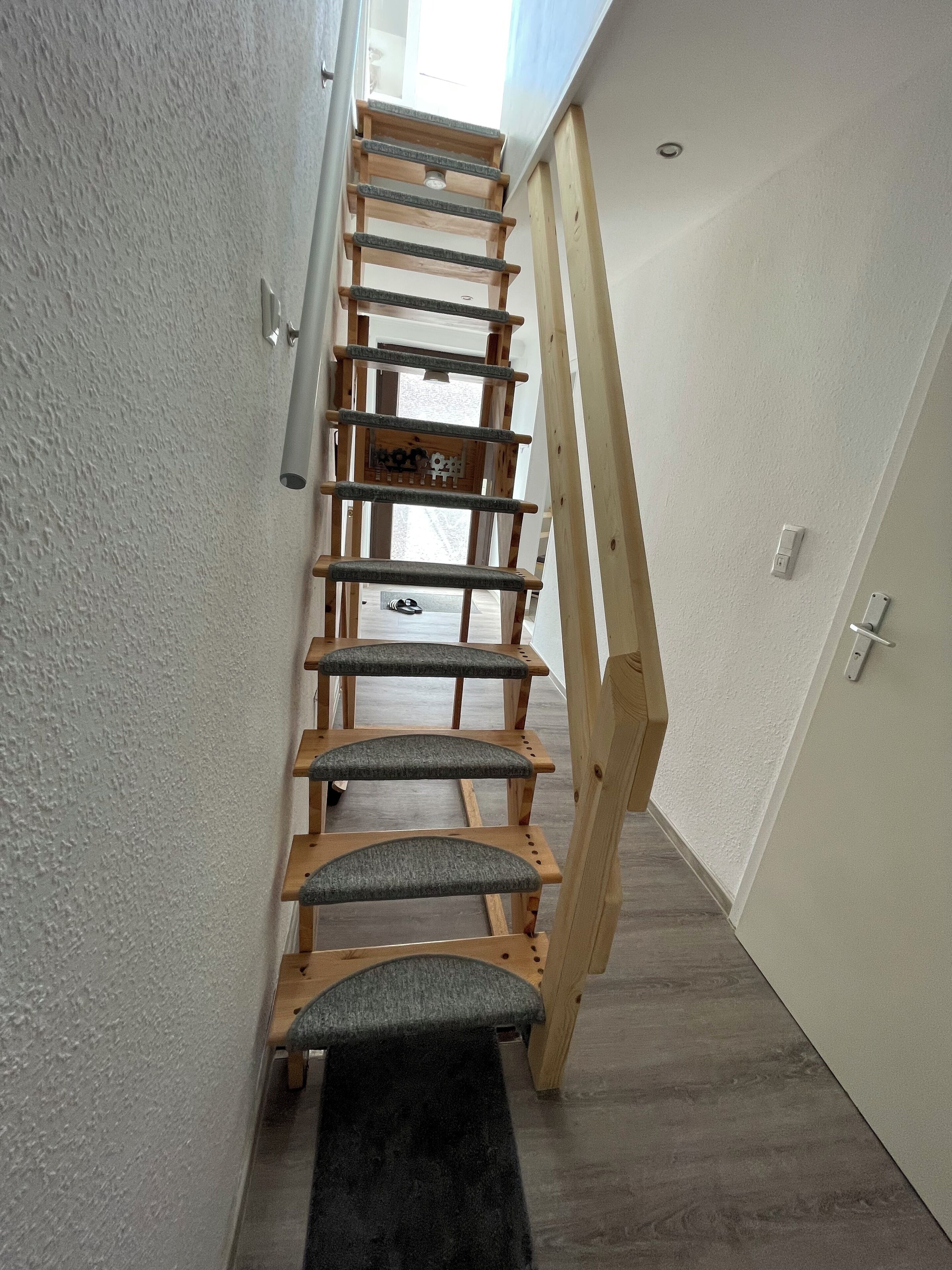 A narrow staircase with wooden steps and grey cushioned handrails.