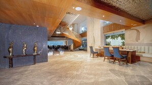 A spacious lobby with a marble floor, a wooden staircase, and a seating area with tables and chairs. - Auradoon Dehradun - By Leisure Hotels (Dehradun)